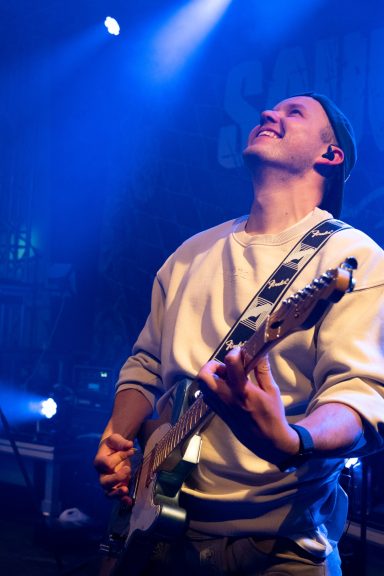 Gitarrist der Partyband Sauwuid während eines Live-Auftritts im blauen Bühnenlicht