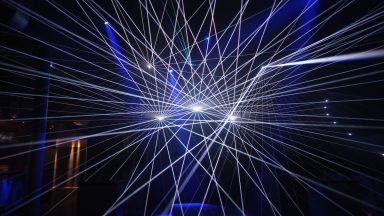 Weißes Lasernetz mit geometrischen Strahlen bei einer Lasershow von LLS