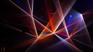 Orange und weiße Laserstrahlen bei einer Lasershow von LLS