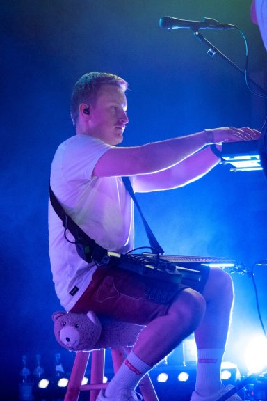 Musiker der Partyband Sauwuid während eines Live-Auftritts im blauen Bühnenlicht am Synthesizer und Bass