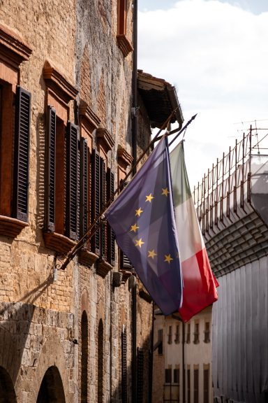 Italienische und europäische Flagge an einer historischen Fassade in San Gimignano