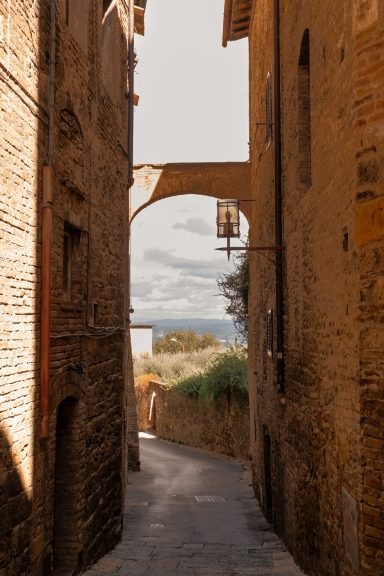 Schmale mittelalterliche Gasse mit Torbogen in San Gimignano, Toskana