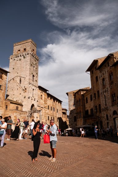 Belebter Platz mit mittelalterlichem Turm in San Gimignano, Toskana
