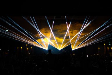 Gelbe und weiße Laserstrahlen bei einer Lasershow der Firma LLS vor Publikum
