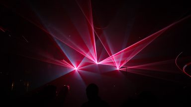 Rote Laserstrahlen und Lichtformationen während einer Lasershow von LLS