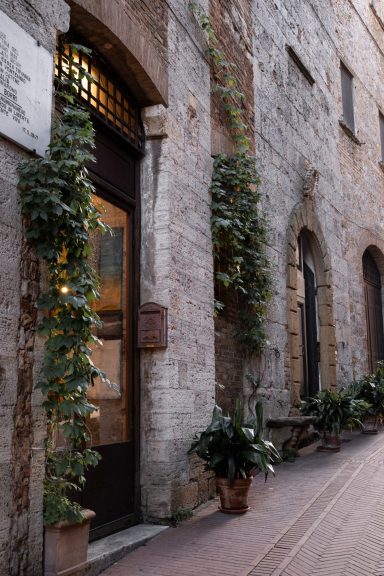 Historische Steinfassade mit bewachsenem Fenster in San Gimignano, Toskana